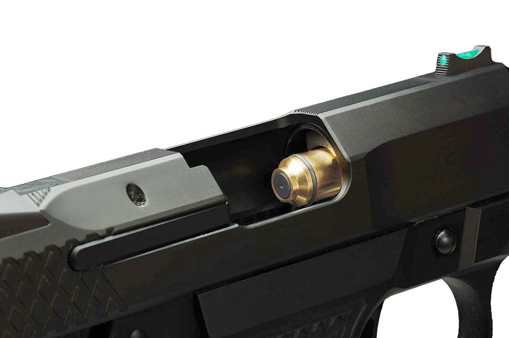 Close-up of a brass laser training cartridge chambered in a 1911-style semi-automatic pistol, with the slide partially retracted to show the cartridge in the chamber.