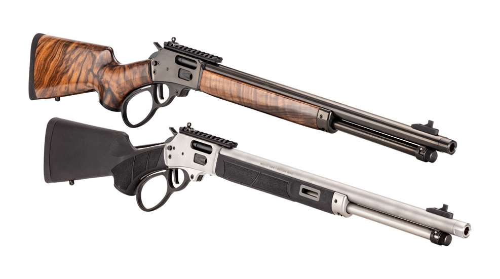Two Henry Protector lever-action carbines displayed diagonally, one with a walnut stock and blued finish, the other with a black synthetic stock and stainless steel barrel and receiver.