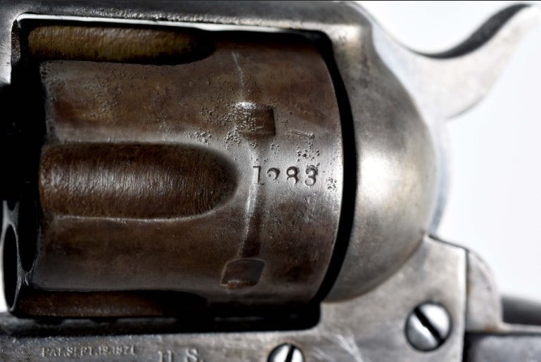 Close-up of a Colt SAA revolver cylinder showing serial number 1283 and bolt notch detail