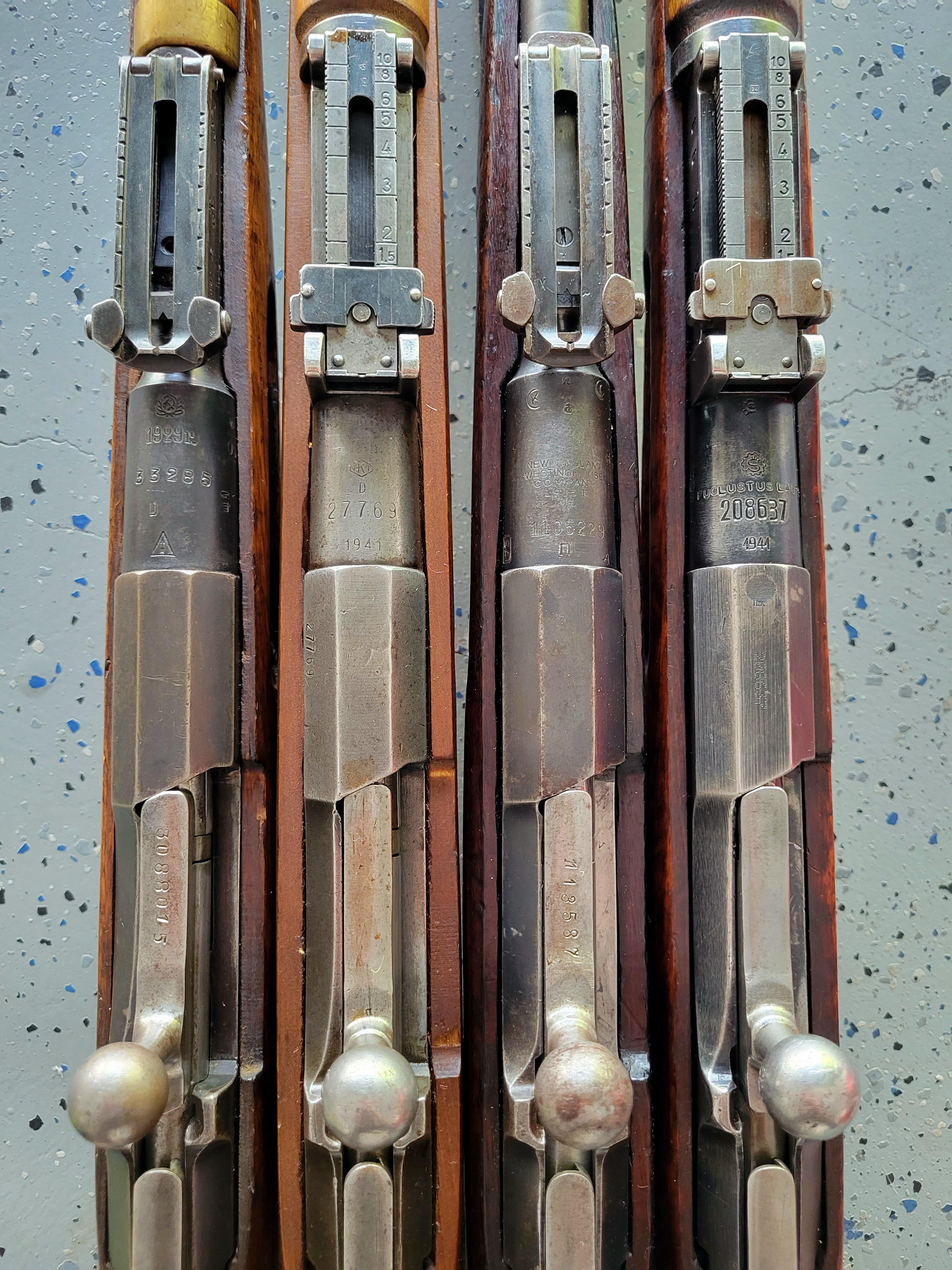 Close-up of four Mosin Nagant 91/30 bolt-action rifle receivers laid parallel, showing hex receiver profiles, serial numbers, and period proof marks including Finnish military markings.