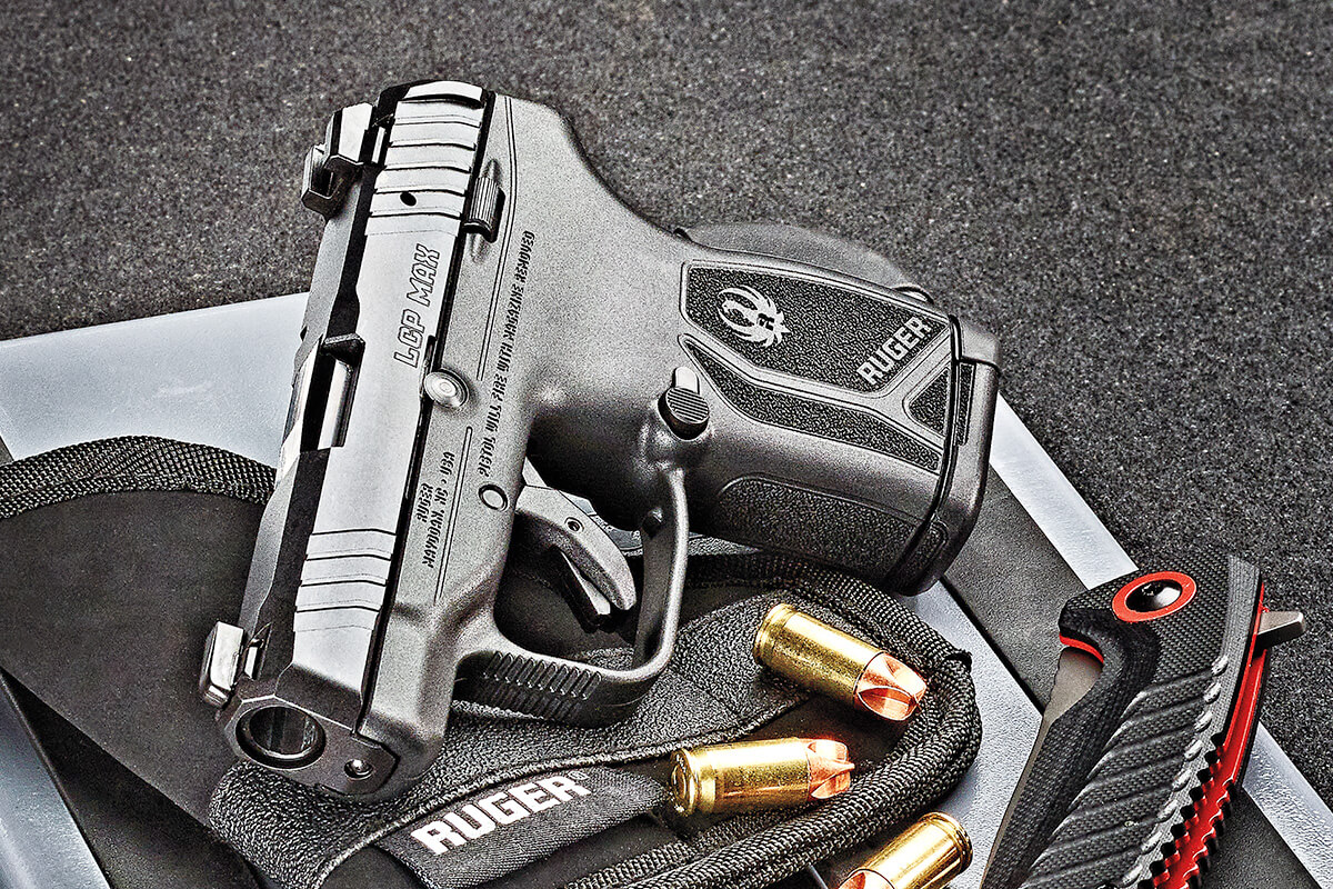 Ruger LCP Max .380 ACP compact pistol resting on a surface with loose hollow-point cartridges nearby