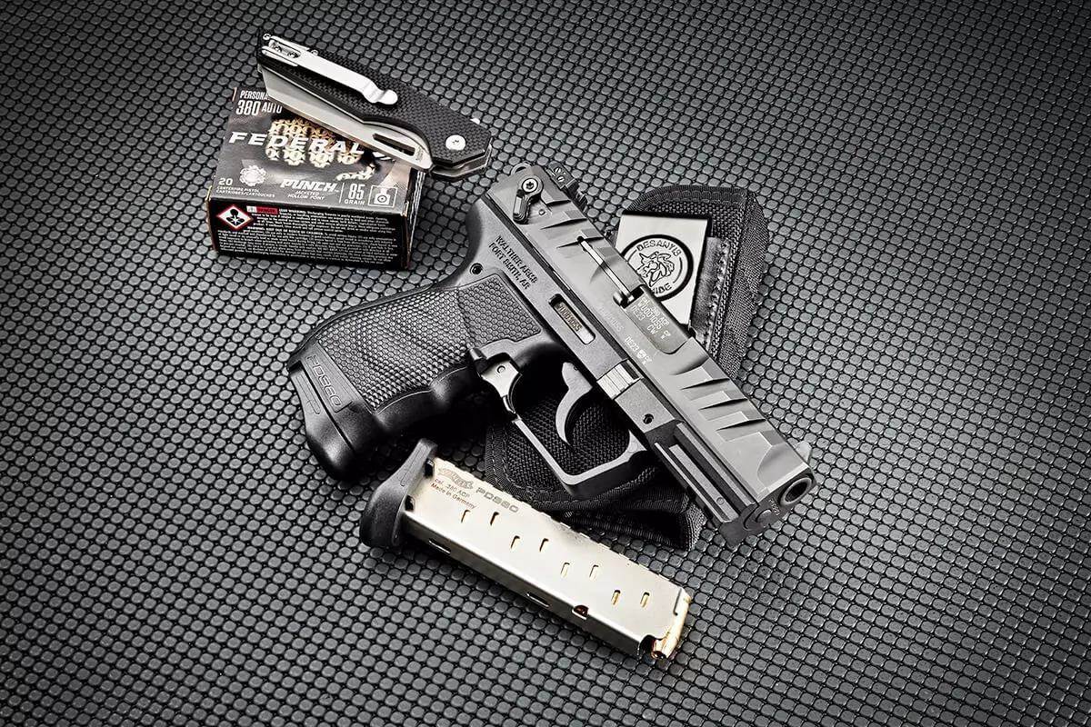 Walther PD380 pistol in .380 ACP shown with a DeSantis holster, spare magazine, and a box of Federal Punch 85-grain .380 Auto ammunition on a textured rubber mat.
