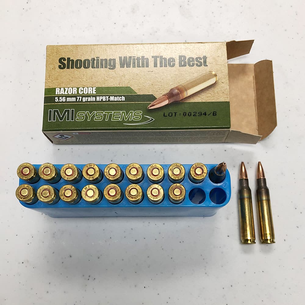 Box of IMI Systems Razor Core 5.56mm 77-grain HPBT-Match ammunition with rounds seated in a blue plastic tray and two loose cartridges displayed beside it.