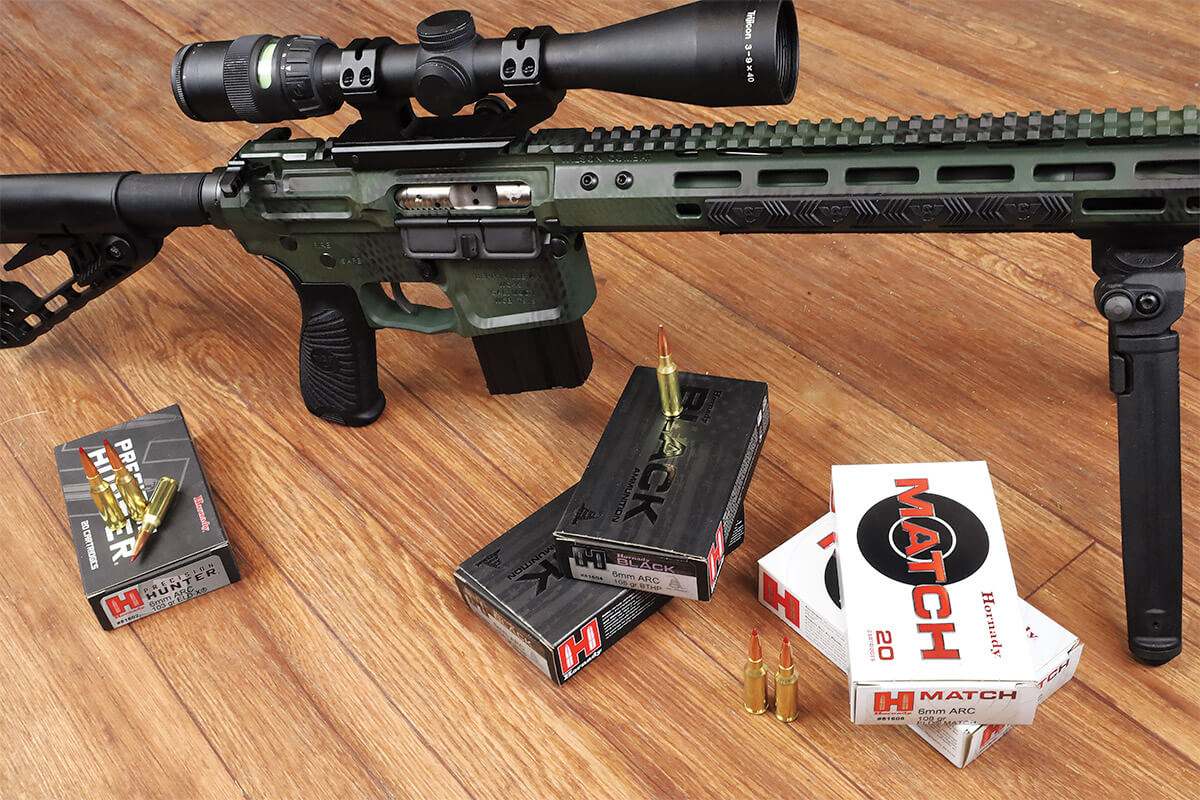 Wilson Combat 6mm ARC AR-style rifle with Trijicon scope and bipod, displayed with three boxes of Hornady 6mm ARC ammunition including Precision Hunter, Black, and Match loads.