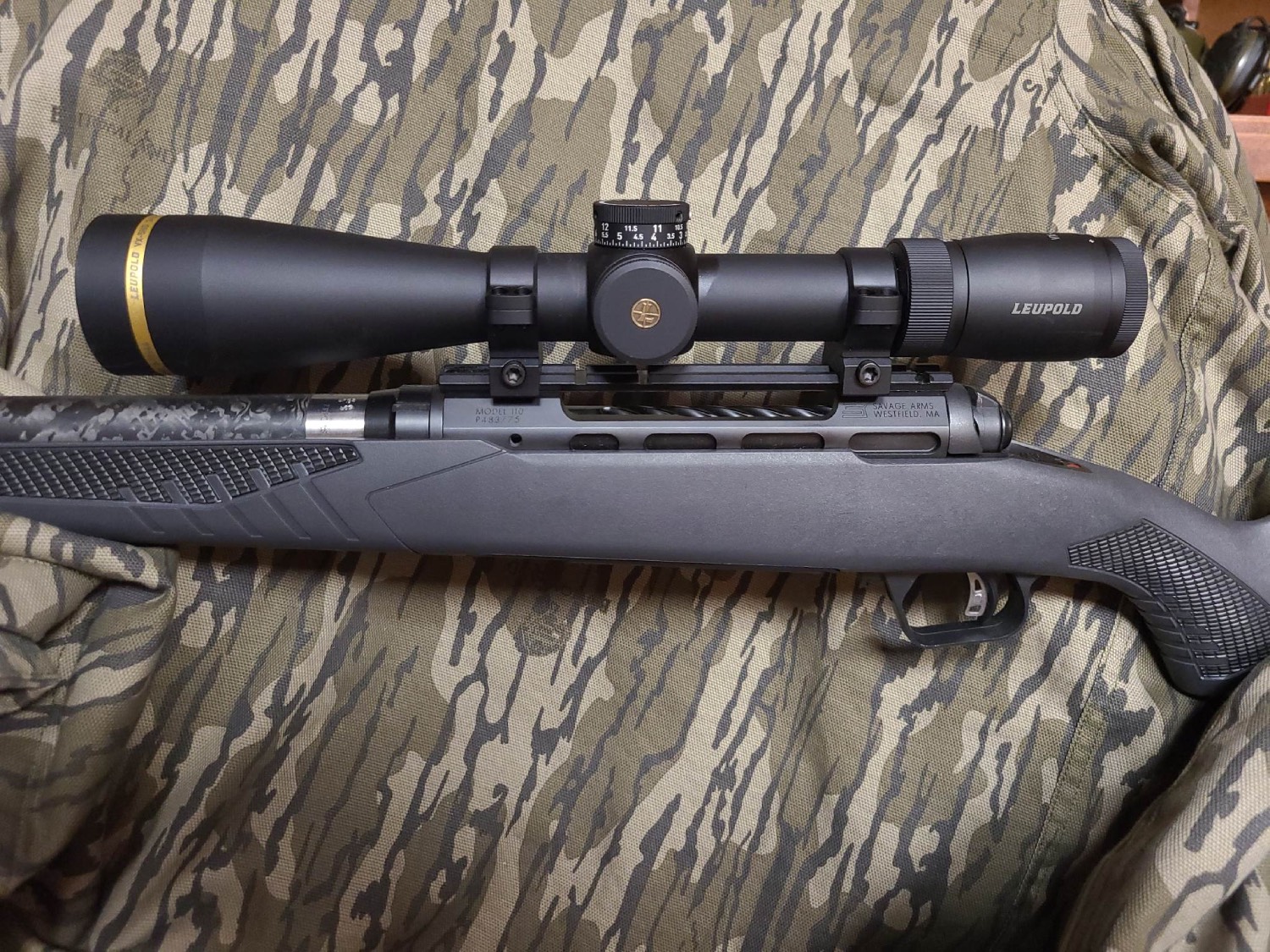 Leupold VX-5HD rifle scope mounted on a Savage Arms Model 110 bolt-action rifle, resting on camouflage fabric.