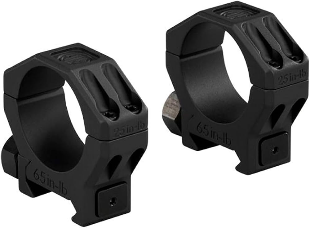 A pair of black aluminum scope rings with torque specifications stamped on the body, shown on a white background.