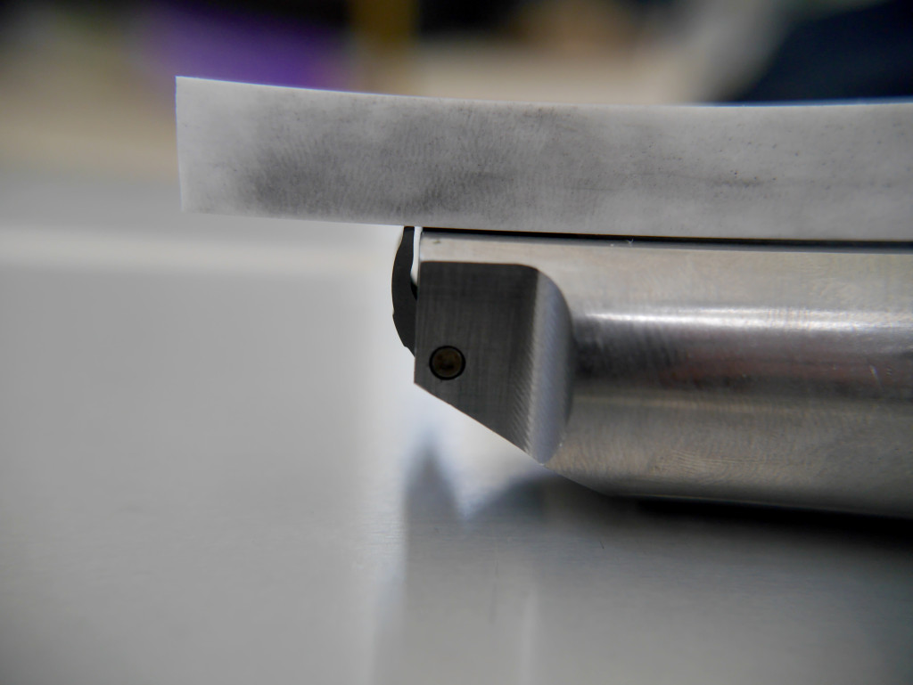 Macro photograph of a stainless 2011 disconnector and frame rail interface, showing the disconnector body, retention screw, and contact surfaces.
