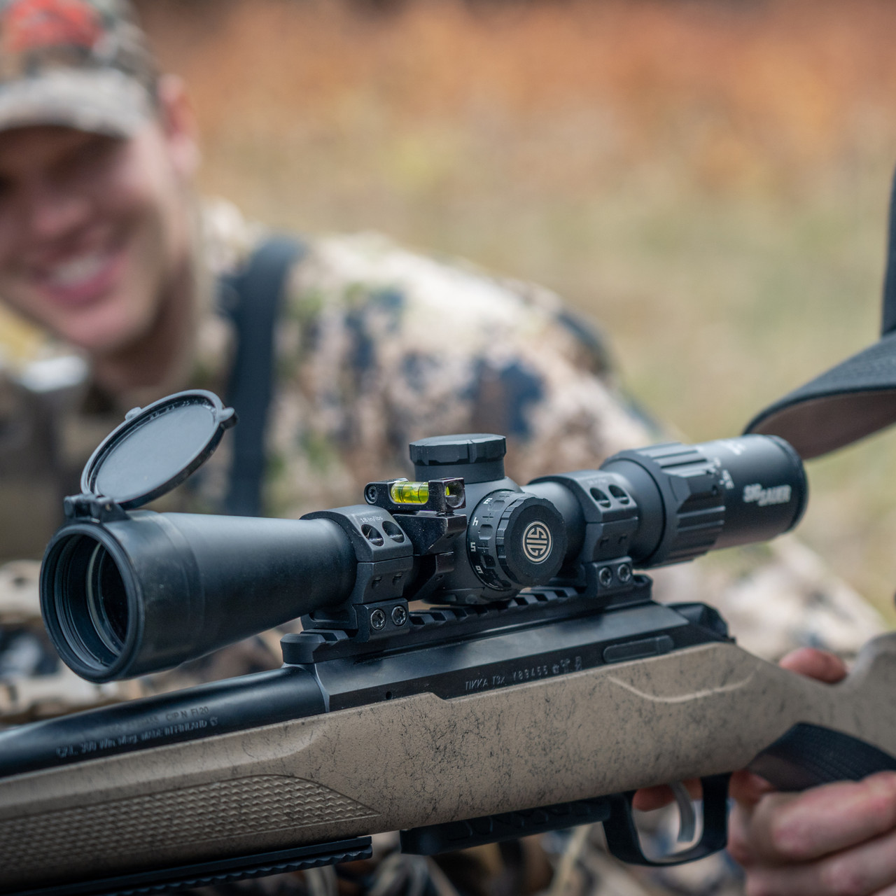 Close-up of a Tikka T3x rifle with a Sig Sauer scope and bubble level mounted on the integrated Picatinny rail.