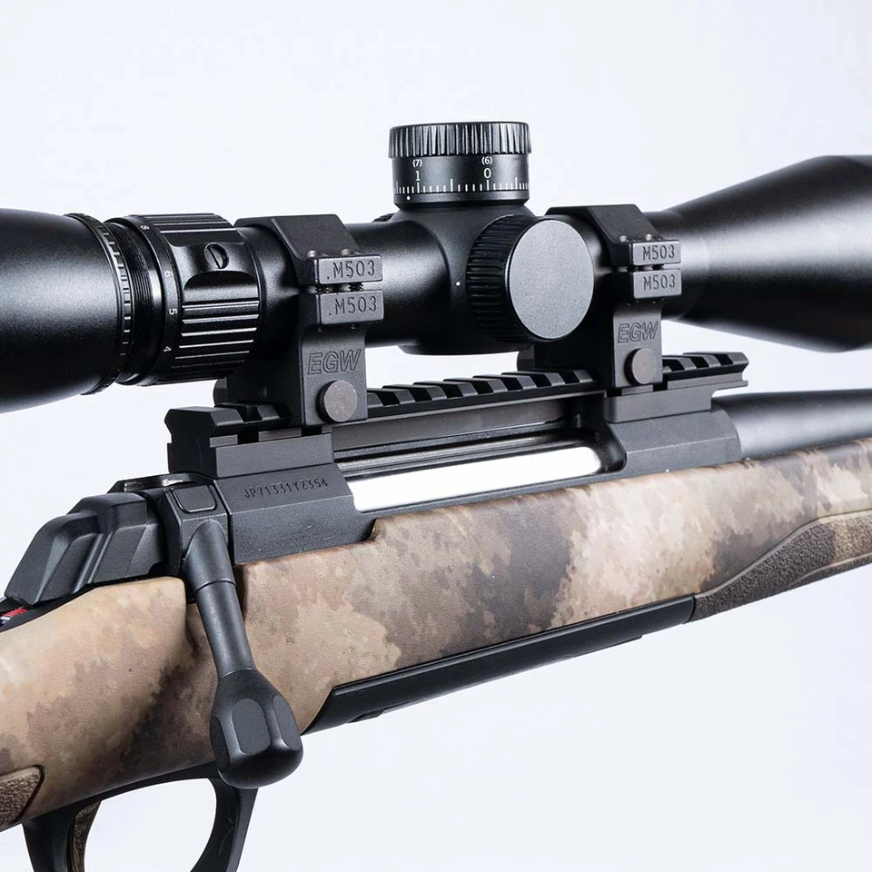 Close-up of EGW M503 scope rings and Picatinny rail mounting a riflescope on a bolt-action rifle with a camouflage stock.