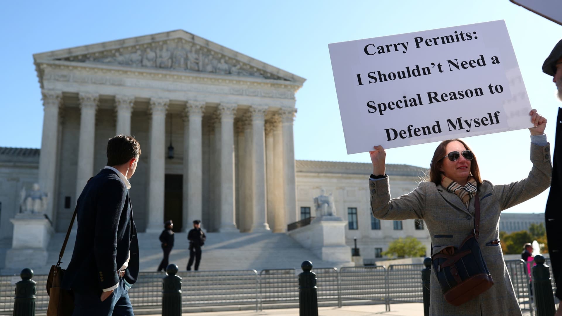 Woman holding a sign reading 'Carry Permits: I Shouldn't Need a Special Reason to Defend Myself' outside the U.S. Supreme Court building.