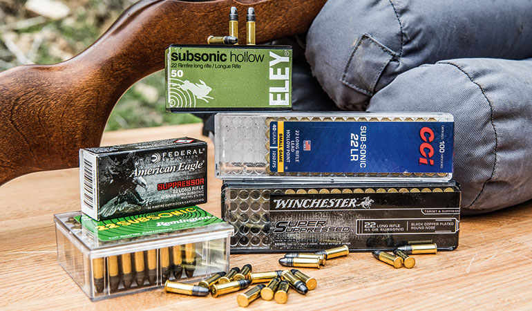 Five boxes of subsonic 22 LR ammunition from various brands arranged on a wooden surface with loose cartridges in front.