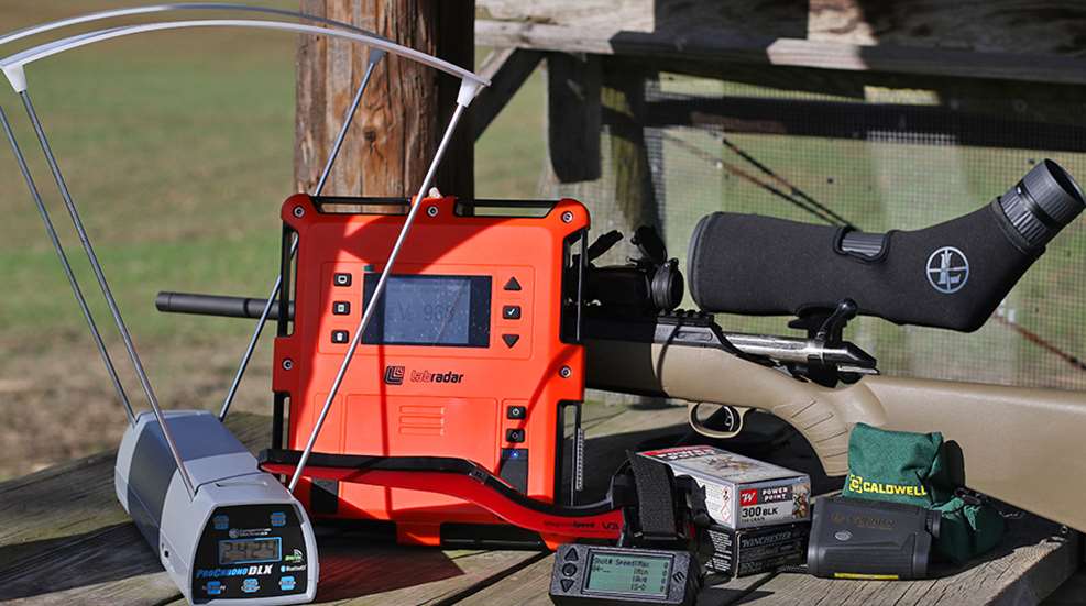 LabRadar Doppler chronograph and MagnetoSpeed on a shooting bench alongside a Leupold spotting scope, Caldwell rear bag, rangefinder, and Winchester 300 BLK ammunition.