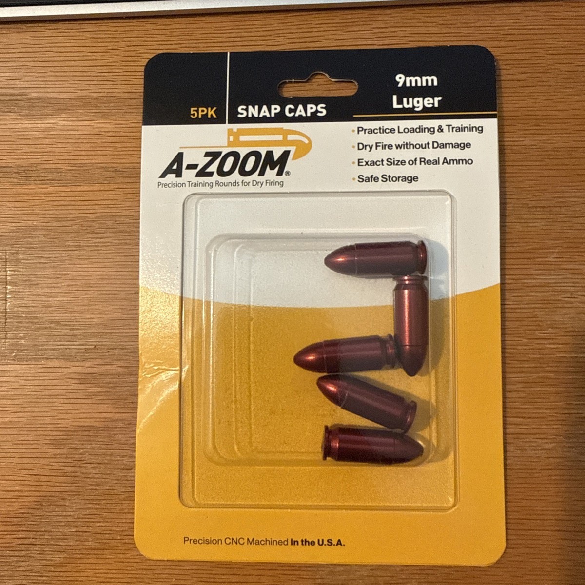 Five-pack of A-Zoom 9mm Luger snap caps in retail blister packaging on a wood surface.