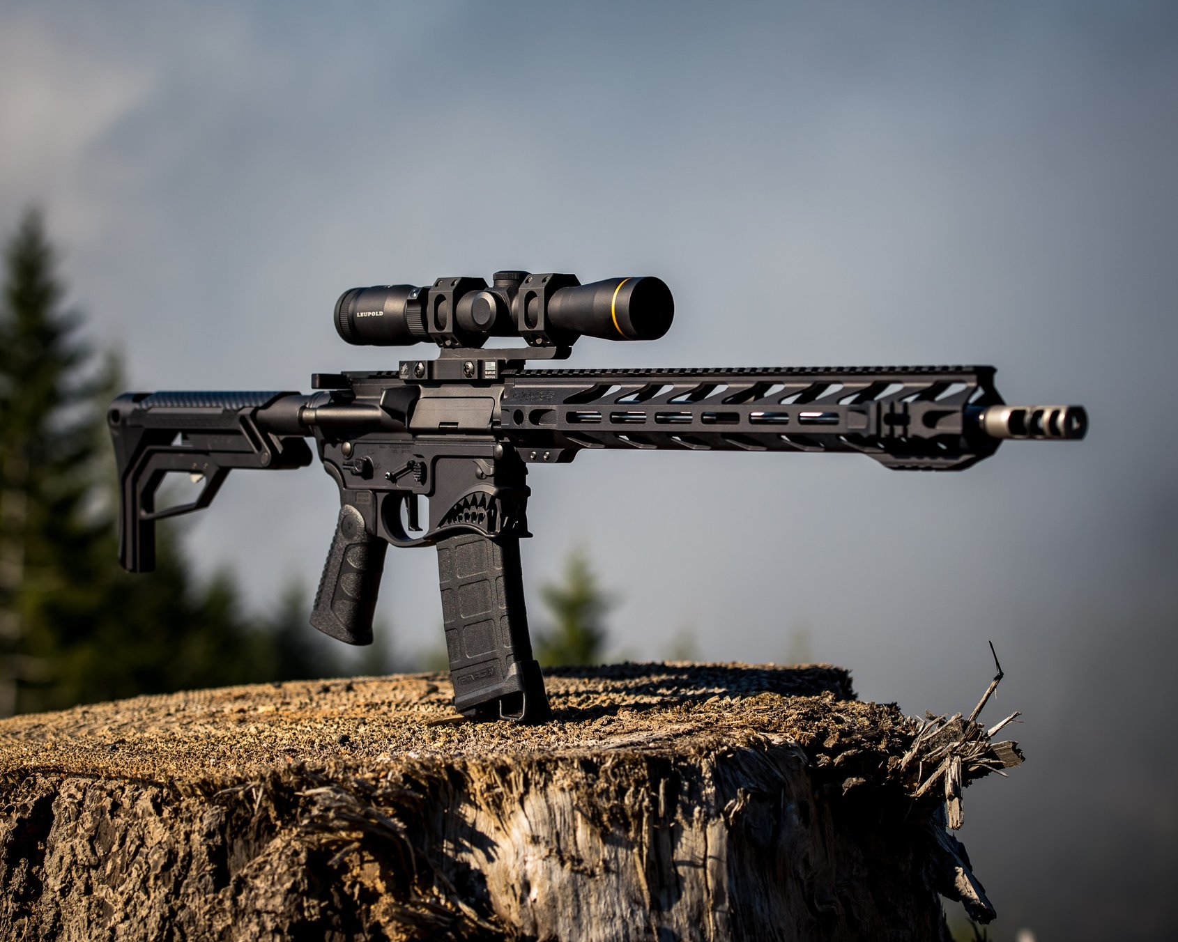 Black AR-15 rifle with Leupold scope and M-LOK handguard resting on a tree stump outdoors.