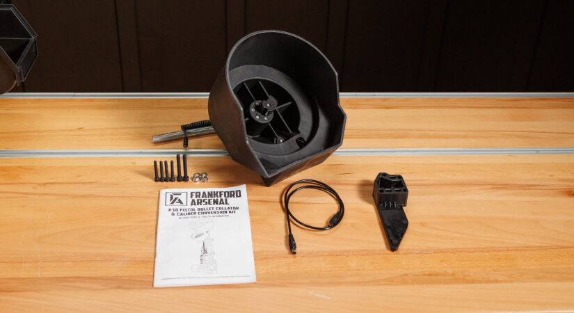 Frankford Arsenal X-10 pistol bullet collator and caliber conversion kit laid out on a wooden workbench, showing the collator bowl, screws, power cable, feed die, and instruction manual.