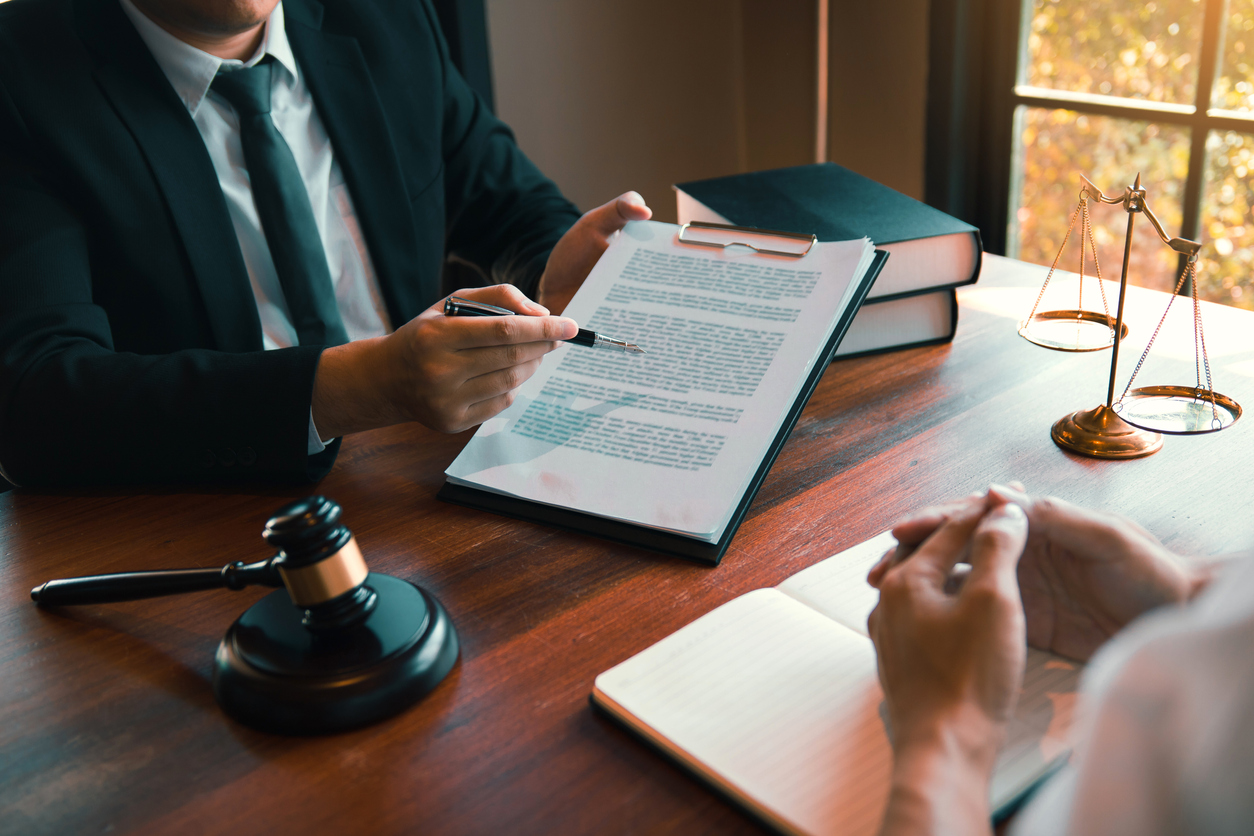 Attorney reviewing legal documents with a client at a desk with a gavel and scales of justice.