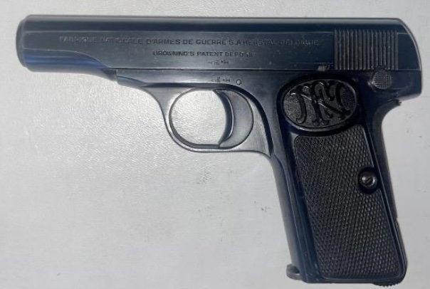 FN Model 1910 semi-automatic pistol in blued finish with checkered grips featuring FN medallion, left side view showing slide markings