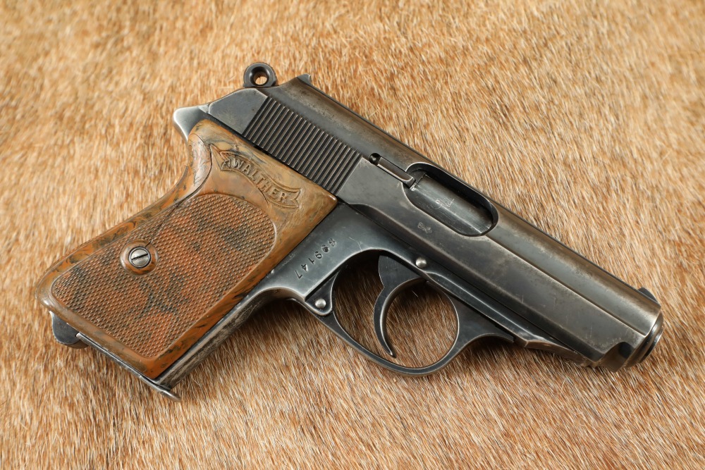 Walther PP semi-automatic pistol with checkered walnut grips and blued finish, displayed on a fur surface, showing pre-war commercial quality.