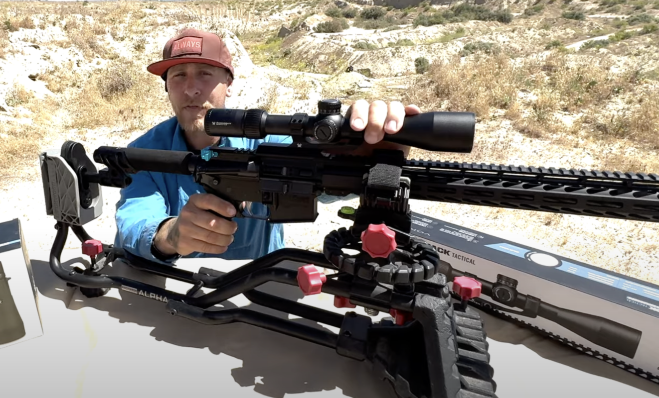 Man holding an AR-style rifle topped with a Vortex Diamondback Tactical scope, rested on a shooting support at an outdoor desert range.