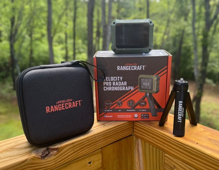 Athlon Rangecraft Velocity Pro Radar Chronograph with carrying case, tripod, and retail box on a wooden deck railing
