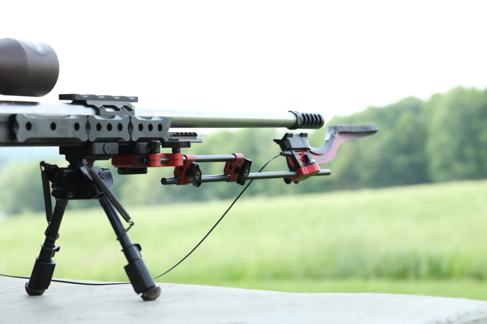 MagnetoSpeed V3 chronograph attached to bolt-action rifle barrel on bipod at outdoor shooting range