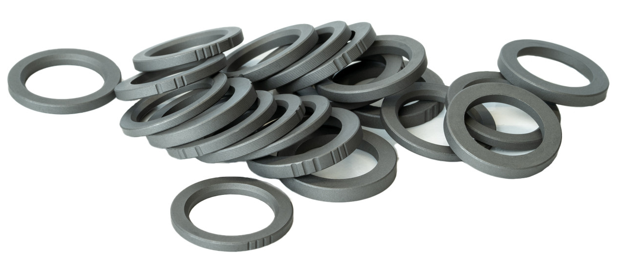 Pile of gray plastic ring spacers used for alignment, similar in concept to muzzle device shim kits