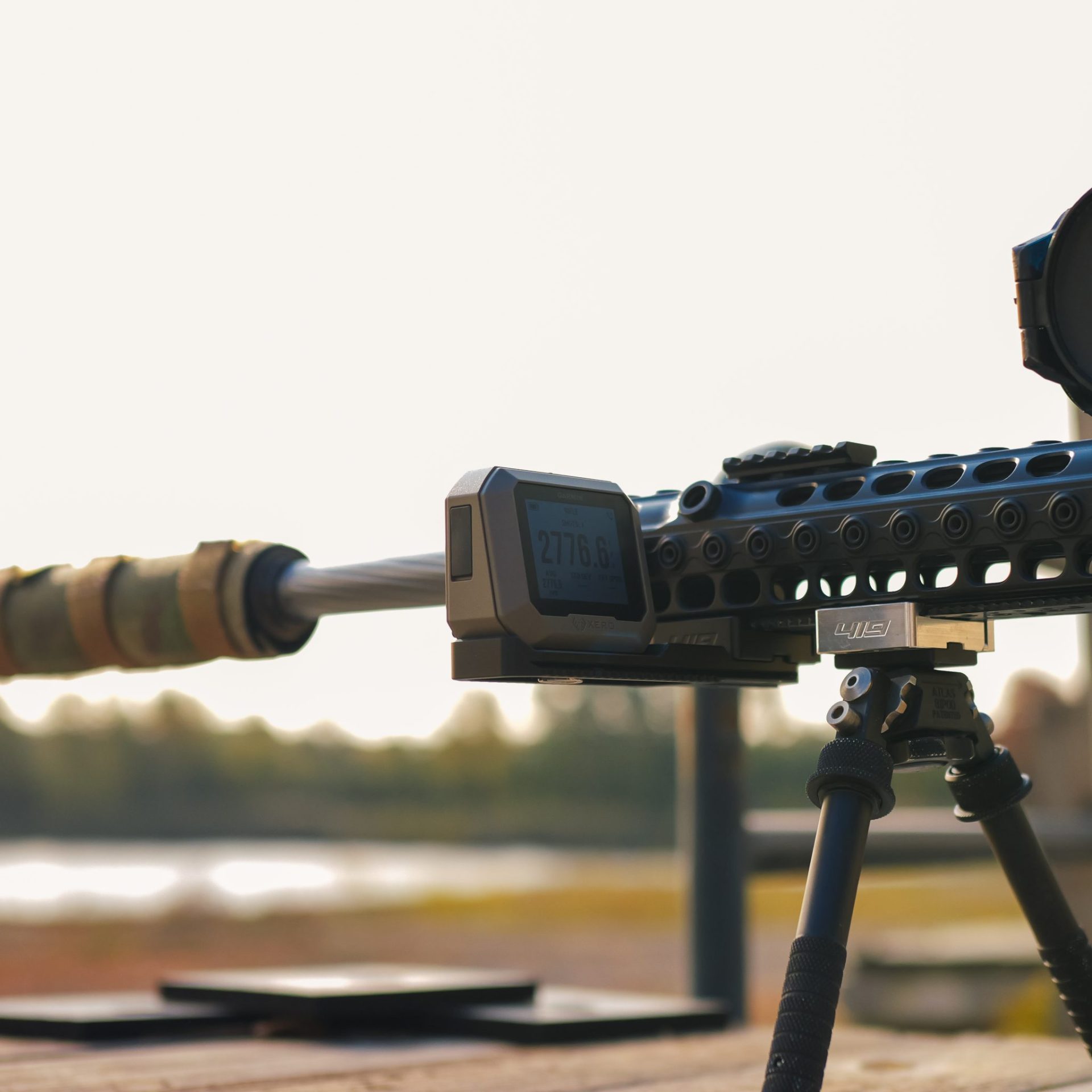 Close-up of a Garmin Xero C1 chronograph mounted near the muzzle of a precision rifle on a tripod, displaying a velocity reading of 2776.6 fps.