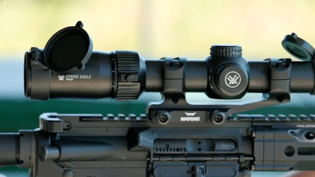 Vortex Strike Eagle 1-6x24 scope mounted on a Daniel Defense AR-style rifle using Warne scope rings, with flip-up lens caps open.