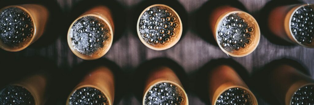 Overhead view of dark glass bottles with liquid and bubbles visible in their openings, arranged in rows.