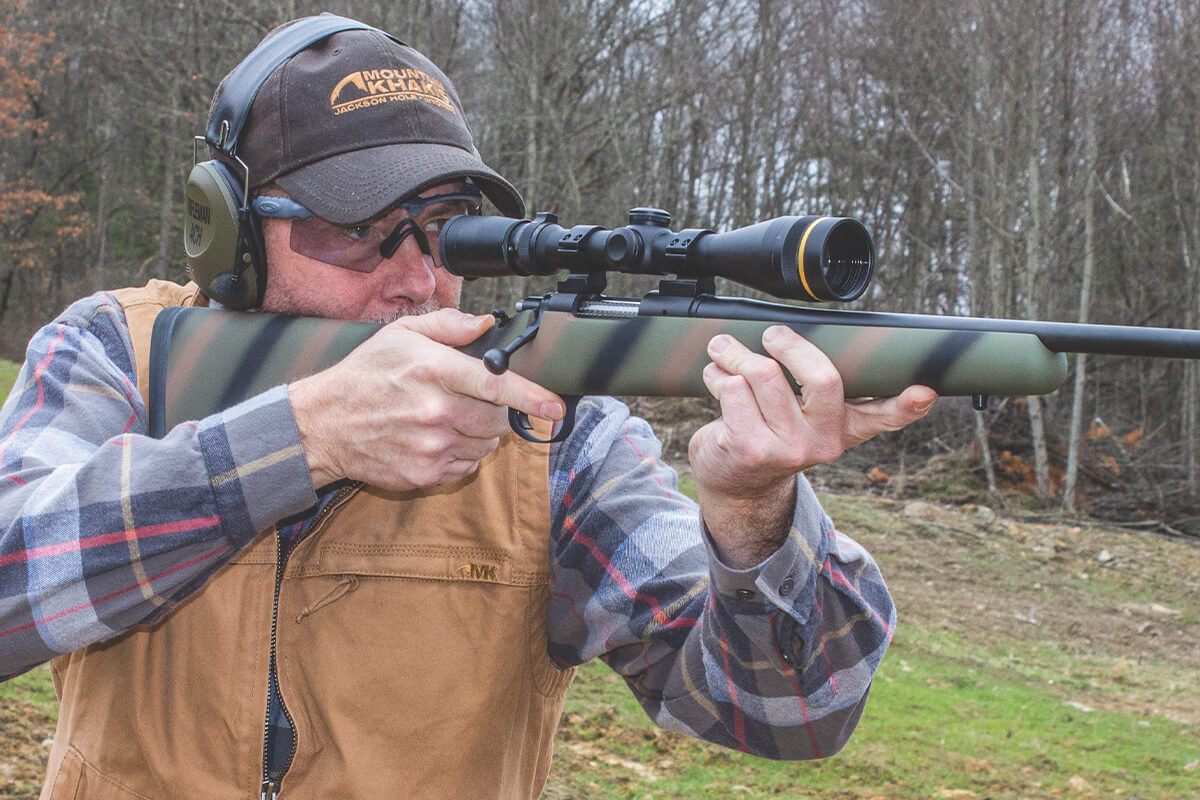 Shooter aiming bolt-action rifle with Leupold scope, demonstrating cheek weld and scope height relationship.