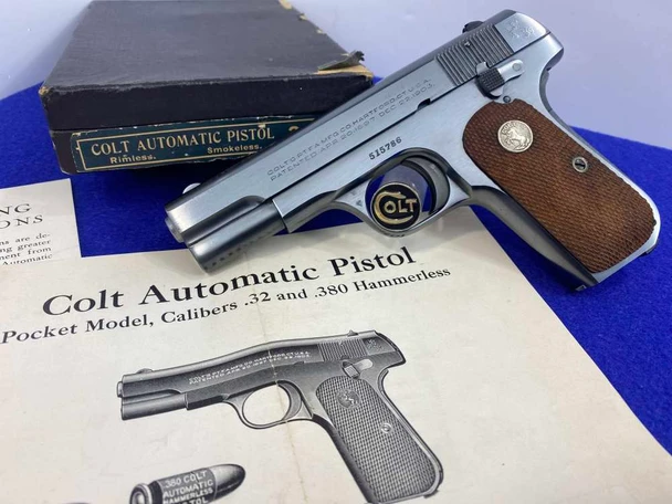 Colt Model 1903 Pocket Hammerless pistol in blued finish with walnut grips, displayed alongside its original black box labeled 'Colt Automatic Pistol Rimless Smokeless' and an open factory instruction manual.